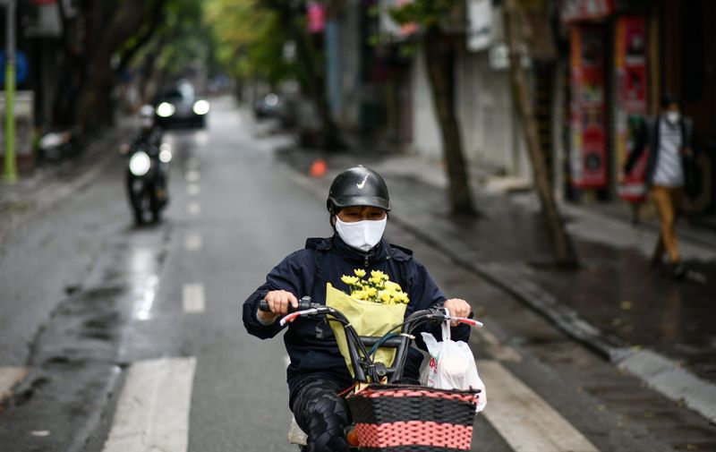 A motorist, wearing a face mask carries flowers on a near-empty street during Vietnam's nationwide "complete social isolation" as a preventive measure against the spread of COVID-19 coronavirus in Hanoi on April 6, 2020., Image: 512529407, License: Rights-managed, Restrictions: , Model Release: no, Credit line: Manan VATSYAYANA / AFP / Profimedia