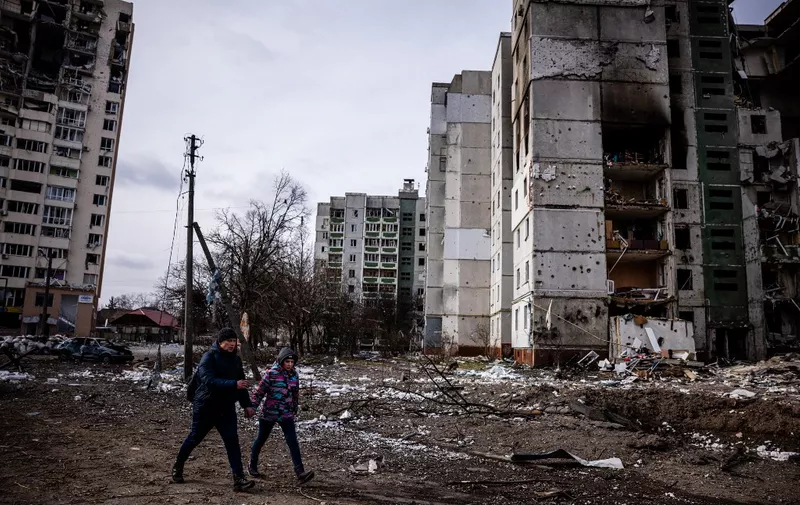 Local residents walk in front of residential buildings damaged in yesterday's shelling in the city of Chernihiv on March 4, 2022. - Fourty-seven people died on March 3 when Russian forces hit residential areas, including schools and a high-rise apartment building, in the northern Ukrainian city of Chernihiv, officials said. (Photo by Dimitar DILKOFF / AFP)