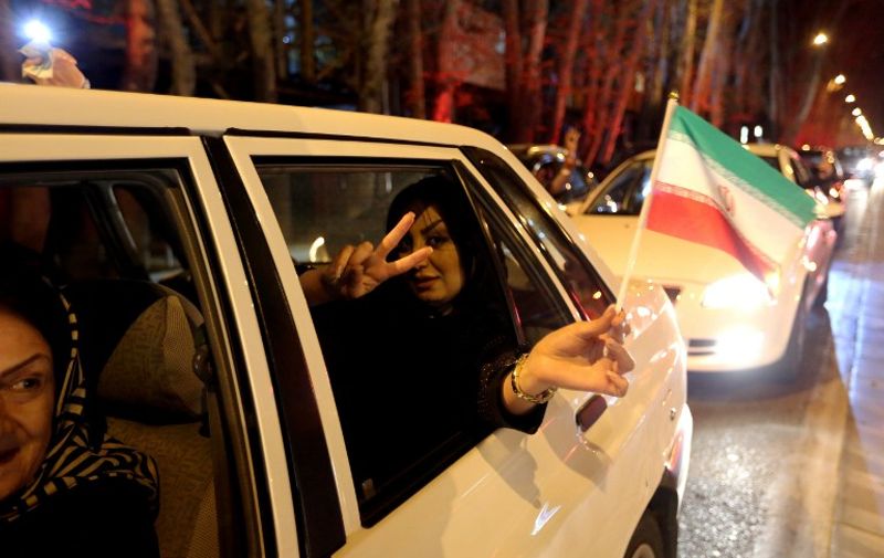 A woman in a car flashes the &#8220;V for Victory&#8221; sign and waves an Iranian flag as people celebrate on Valiasr street in northern Tehran on April 2, 2015, after the announcement of an agreement on Iran nuclear talks. Iran and global powers sealed a deal on April 2 on plans to curb Tehran&#8217;s chances [&hellip;]