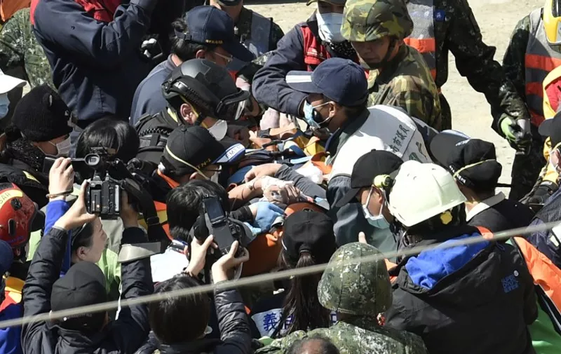 A 40-year-old man (C), identified by local media as Lee Tsung-tian, is checked by medical personnel after being rescued from the rubble at the Wei-Kuan complex which collapsed in the 6.4 magnitude earthquake, in the southern Taiwanese city of Tainan on February 8, 2016. Two survivors were on February 8 rescued from the rubble of an apartment complex in Taiwan felled by an earthquake, after being trapped for more than 50 hours.       AFP PHOTO / Sam Yeh / AFP / SAM YEH