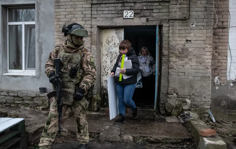 Members of a local election commission, accompanied by a serviceman, visit voters during early voting in Russia's presidential election in Donetsk, Russian-controlled Ukraine, amid the Russia-Ukraine conflict on March 14, 2024. (Photo by STRINGER / AFP)