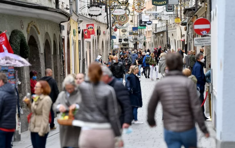 People walk in the shopping street 'Getreidegasse' in the old town in Salzburg, Austria on May 2, 2020. - Austrian citizens are allowed to leave the house for non-essential trips as it eases coronavirus lockdown measures, but said limits on gatherings and social distancing rules would remain in place. From May 2, 2020, shopping centres, hairdressers and all shops with more than 400 square metres of sales area are allowed to reopen, including the major electrical retailers, fashion chains, furniture stores and sports equipment retailers. (Photo by BARBARA GINDL / APA / AFP) / Austria OUT