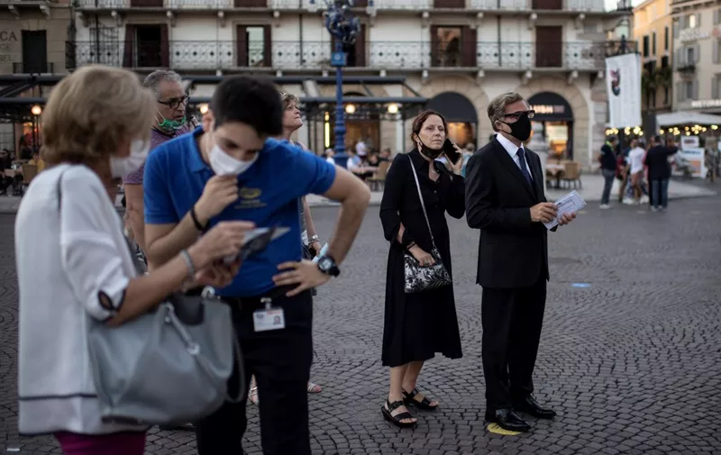Guests wearing face masks wait as they arrive before a concert at the Arena in Verona, northern Italy, on July 25, 2020. - This is the first show with new dispositions against the spread of the novel coronavirus (Covid-19) during this season. (Photo by MARCO BERTORELLO / AFP)