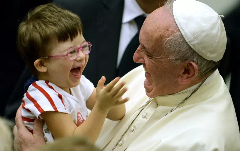 Pope Francis (R) greets a boy during an audience with parish cells for the evangelization in Paul VI hall at the Vatican on September 5, 2015.   AFP PHOTO / FILIPPO MONTEFORTE