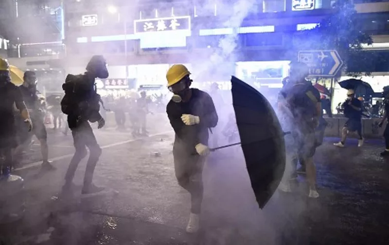 Protesters are enveloped by tear gas let off by police during a demonstration against a controversial extradition bill in Hong Kong on July 28, 2019. - Tens of thousands of pro-democracy protesters defied authorities to hold an unsanctioned march through Hong Kong, a day after riot police fired rubber bullets and tear gas to disperse another illegal gathering, plunging the financial hub deeper into crisis. (Photo by Anthony WALLACE / AFP)
