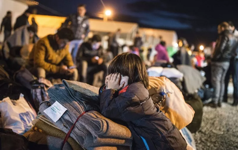 A child looks on as migrants and refugees rest in a camp as they wait for a train to Serbia near Gevgelija on the Greek - Macedonian border on February 25, 2016. 
Balkan countries along the well-trodden migrant path towards northern Europe met on February 24 to explore ways to stem the flow despite growing fears that tighter controls will spark a humanitarian crisis, particularly in Greece. / AFP / Robert ATANASOVSKI