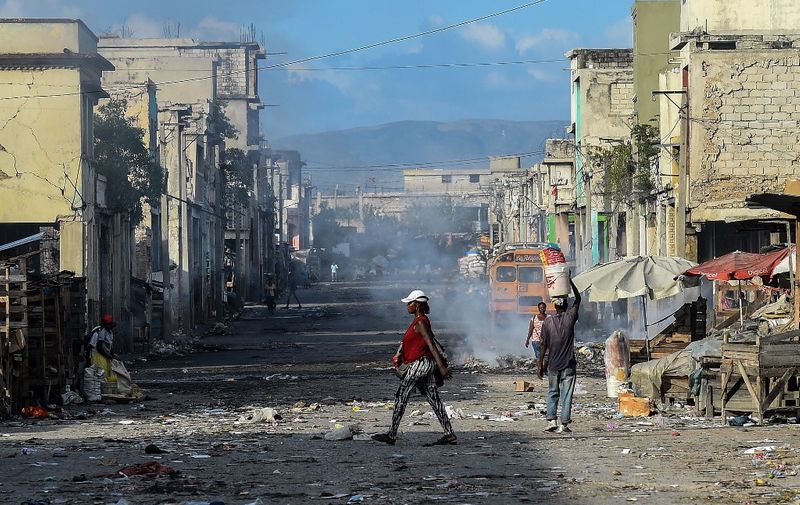 (FILES) In this file photo taken on December 20, 2019, eople walk on the deserted road ahead of gang shootings in downtown in Port-au-Prince. - Long confined to the slums, the gangs have gradually extended their control in Haiti and the nearly three million inhabitants of Port-au-Prince are forced to adapt their daily lives to this reality, for fear of being the next victim. "The gangs today reign supreme and lords over the country," laments Gédéon Jean, director of the Center for Analysis and Research in Human Rights, based in the Haitian capital. (Photo by CHANDAN KHANNA / AFP)