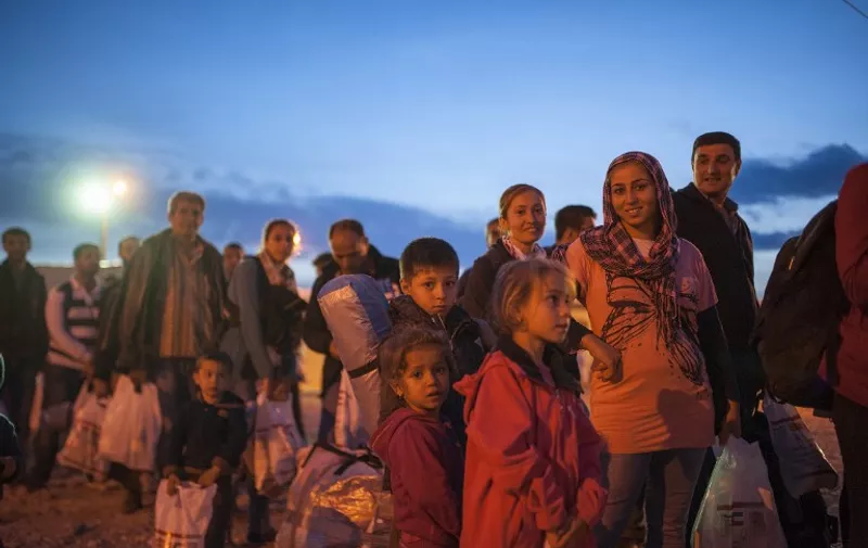 Migrants and asylum seekers wait  to enter a registration camp after crossing the Greece-Macedonia border near Gevgelija, southeastern Macedonia, on October 6, 2015. Macedonia is a key transit country in the Balkans migration route into the European Union, with thousands of asylum seekers and migrants - many of them from Syria, Afghanistan, Iraq and Somalia - entering the country every day. The EU said a controversial programme to relocate 40,000 refugees within the bloc from overstretched frontline states would formally start on October 9 when a group of Eritreans will travel to Sweden from Italy. AFP PHOTO / ROBERT ATANASOVSKI