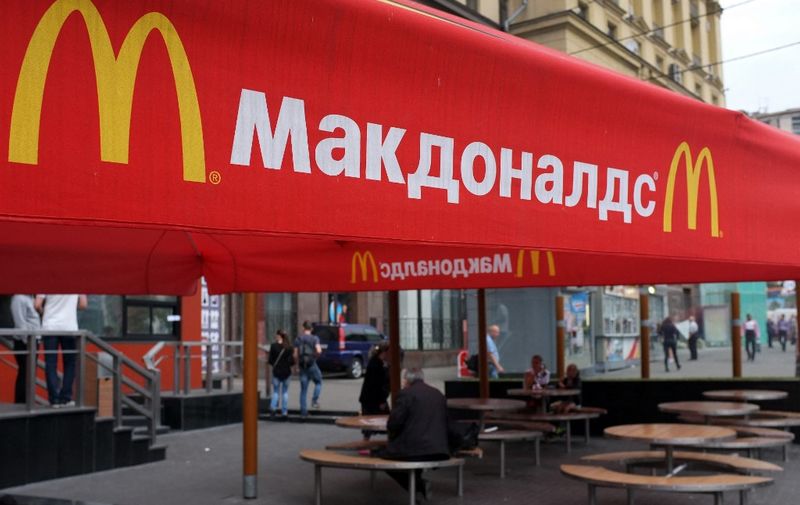 People sit on the terrace of a closed McDonald's restaurant, the first to be opened in the Soviet Union in 1990, in Moscow on August 21, 2014. Russian authorities shuttered four Moscow McDonald's due to alleged sanitary violations on August 20, 2014, including a restaurant that once symbolised reviving Soviet-US ties, as tensions sizzled over Ukraine.  The announcement comes in the wake of Russian bans on US and EU food imports in response to Western sanctions over Moscow's perceived backing for rebels in eastern Ukraine.
AFP PHOTO / ALEXANDER NEMENOV (Photo by ALEXANDER NEMENOV / AFP)