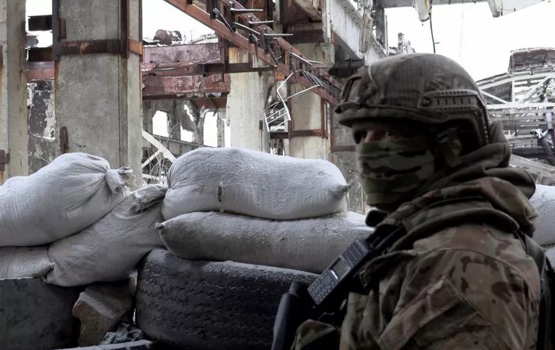 A serviceman of Ukrainian Military Forces stands guard at the destroyed industrial zone in town of Avdiivka on the front-line with Russia-backed separatists, on February 9, 2022. - The hope of avoiding a war in Ukraine grew on February 9, 2022 after the intense diplomatic activity of the last few days, which offers "real chances" of de-escalation according to Kiev, the Kremlin as well as the West noting first positive signals (Photo by Will VASSILOPOULOS / AFP)