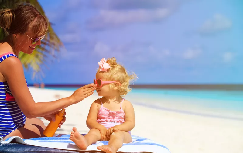 mother applying sunblock cream on daughter shoulder, sun protection