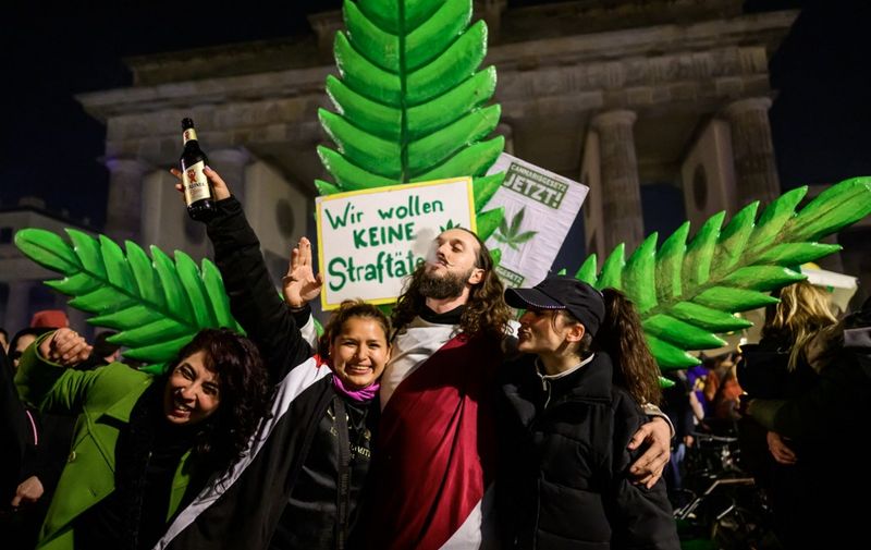 Marijuana smokers celebrate in front of a giant mock marijuana plant at a demonstration outside Berlin's Brandenburg Gate to mark the coming into force in Germany on April 1, 2024 of a law allowing adults to carry up to 25 grams of dried cannabis and grow up to three marijuana plants at home. (Photo by John MACDOUGALL / AFP)