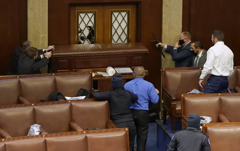 WASHINGTON, DC - JANUARY 06: U.S. Capitol police officers point their guns at a door that was vandalized in the House Chamber during a joint session of Congress on January 06, 2021 in Washington, DC. Congress held a joint session today to ratify President-elect Joe Biden's 306-232 Electoral College win over President Donald Trump. A group of Republican senators said they would reject the Electoral College votes of several states unless Congress appointed a commission to audit the election results.   Drew Angerer/Getty Images/AFP1