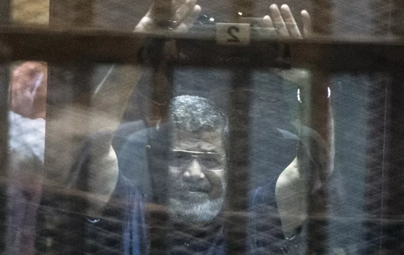 TOPSHOTS
Egypt's deposed Islamist president Mohamed Morsi raises his hands from behind the defendant's cage as the judge reads out his verdict sentencing him and more than 100 other defendants to death at the police academy in Cairo on May 16, 2015. AFP PHOTO / KHALED DESOUKI