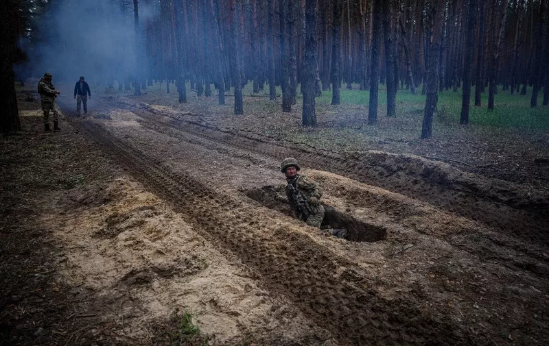 A Ukrainian serviceman lies in a trench during a military exercise in the Kharkiv region on May 1, 2023, amid the Russian invasion of Ukraine. (Photo by Dimitar DILKOFF / AFP)