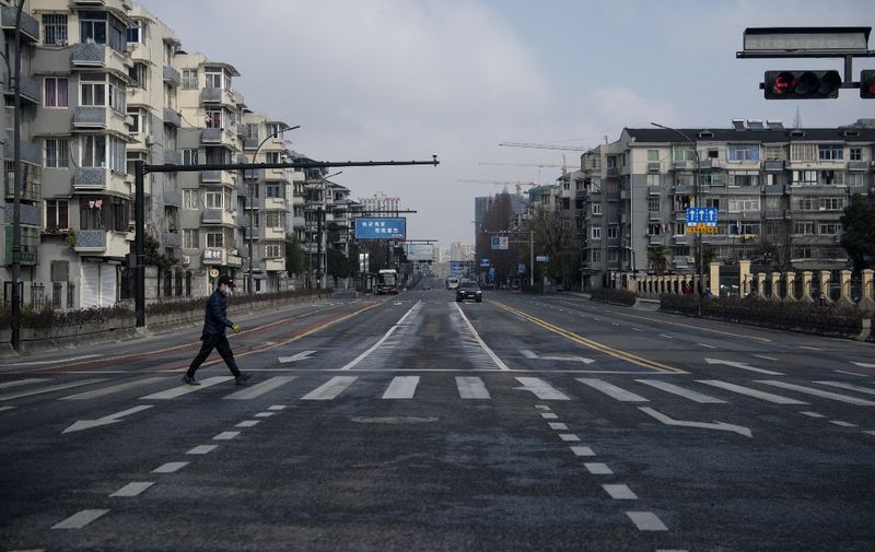 A man wearing a protective facemask walks on an empty street in Hangzhou, some 175 kilometres (110 miles) southwest of Shanghai on February 5, 2020, near Alibaba headquarters. - The world has a "window of opportunity" to halt the spread of a deadly new virus, global health experts said, as the number of people infected in China jumped to 24,000 and millions more were ordered to stay indoors. (Photo by NOEL CELIS / AFP)