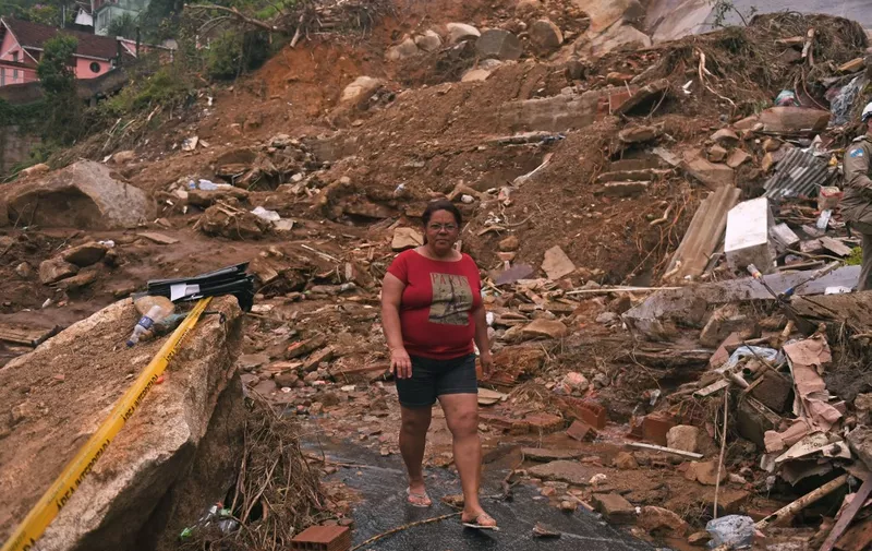 A woman walks through the wreckage of a giant landslide in Petropolis, Brazil, on February 19, 2022. - A total of 136 bodies have been retrieved to date, according to civil defense officials, in the normally scenic tourist town some 60 kilometers (37 miles) north of Rio de Janeiro. (Photo by MAURO PIMENTEL / AFP)