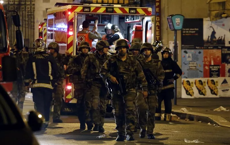 Soldiers walk in front of an ambulance as rescue workers evacuate victims near La Belle Equipe, rue de Charonne, at the site of an attack on Paris on November 14, 2015 after a series of gun attacks occurred across Paris as well as explosions outside the national stadium where France was hosting Germany. More than 100 people were killed in a mass hostage-taking at a Paris concert hall and many more were feared dead in a series of bombings and shootings, as France declared a national state of emergency.  AFP PHOTO / PIERRE CONSTANT