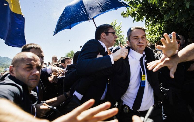 Bodyguards try to protect Serbian Prime Minister Aleksandar Vucic (C) from stones hurled at him by an angry crowd at the Potocari Memorial Center, near the eastern Bosnian town of Srebrenica on July 11, 2015. Tens of thousands of people gathered in Srebrenica on July 11 to commemorate the 20th anniversary of the massacre of thousands of Muslims in the worst mass killing in Europe since World War II. Serbian Prime Minister Aleksandar Vucic was forced to flee the Srebrenica memorial when the crowd started to chant 'Allahu Akbar' (God is Great) and to throw stones. AFP PHOTO / DIMITAR DILKOFF
