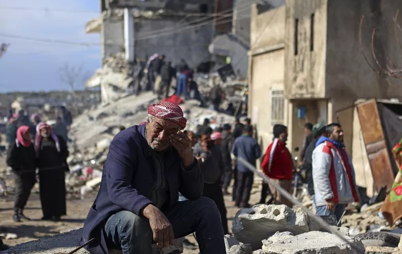 A Syrian man cries as he sits on the rubble of a collapsed building in the rebel-held town of Jindayris on February 7, 2023, following a deadly quake. - The Syrian Red Crescent appealed to Western countries to lift sanctions and provide aid after a powerful earthquake has killed more than 1,600 people across the war-torn country. The 7.8-magnitude quake early the previous day, which has also killed thousands in neighbouring Turkey, led to widespread destruction in both regime-controlled and rebel-held parts of Syria. (Photo by AAREF WATAD / AFP)