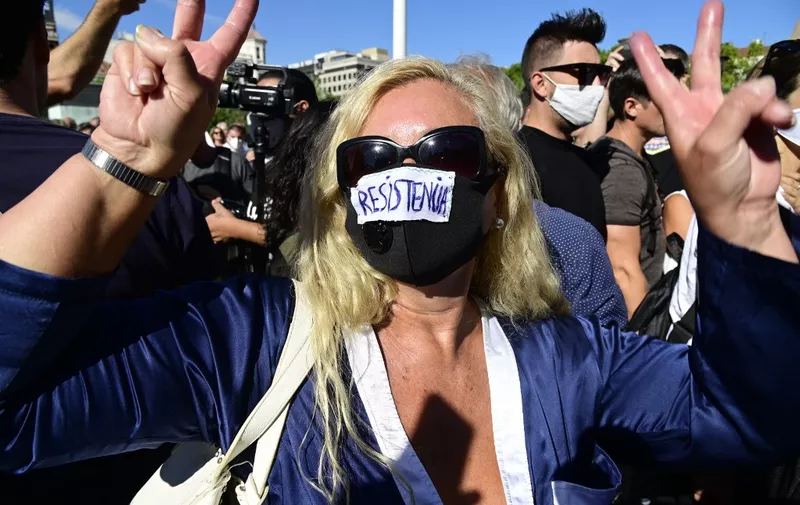 A woman poses sporting a face mask with the word "Resistence" on it during a demonstration against the mandatory use of face masks as well as other measures adopted by the Spanish government to fight against coronavirus in Spain, on August 16, 2020, at the Colon square in Madrid. - New restrictions to stop the spread of the new coronavirus, including the closure of discos and a partial ban on smoking outdoors, went into effect today in two Spanish regions as part of a raft of new measures which Spain's Health Minister Salvador Illa unveiled on August 14, 2020 to be enforced nationwide as the country battles a surge in the disease. (Photo by JAVIER SORIANO / AFP)