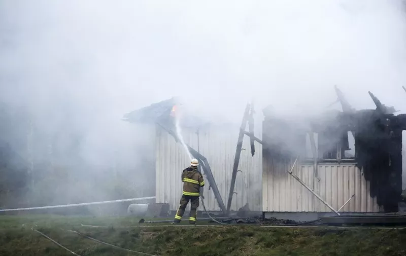 A firefighter works to extinguish a fire that broke out early in the morning on October 20, 2015 at an accommodation for asylum seekers near Munkedal in Sweden. The fire was the fourth in just over a week in Sweden that has affected shelters that housed or planned to house asylum seekers. AFP PHOTO / TT NEWS AGENCY / Adam Ihse  +++ SWEDEN OUT