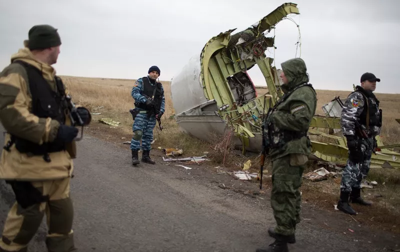 (FILES) In this file photo taken on November 11, 2014, pro-Russian gunmen guard as Dutch investigators (unseen) arrive near parts of the Malaysia Airlines Flight MH17 at the crash site near the Grabove village in eastern Ukraine, hoping to recover debris from the Malaysia Airlines plane which crashed in July, killing 298 people, in remote rebel-held territory east of Donetsk. - A Dutch court gives its verdict on November 17, 2022 in the trial of four men over the downing of Malaysia Airlines flight MH17 above Ukraine in 2014, as tensions soar over Russia's invasion eight years later. All 298 passengers and crew were killed when the Boeing 777 flying from Amsterdam to Kuala Lumpur was hit over separatist-held eastern Ukraine by what investigators say was a missile supplied by Moscow. (Photo by Menahem KAHANA / AFP)
