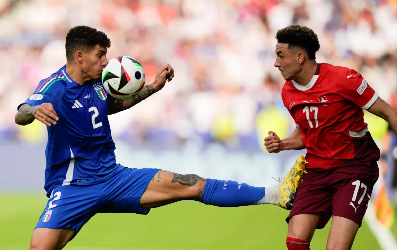 The ball deflects off Italy's Giovanni Di Lorenzo's face next to Switzerland's Ruben Vargas during a round of sixteen match between Switzerland and Italy at the Euro 2024 soccer tournament in Berlin, Germany, Saturday, June 29, 2024. (AP Photo/Matthias Schrader)