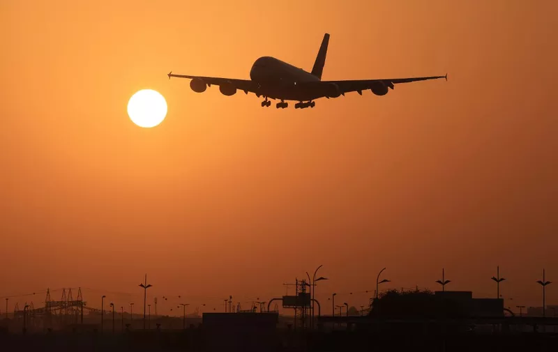 An Emirates Airlines plane lands at Dubai International Airport at sunrise in Dubai on October 17, 2023. (Photo by Karim SAHIB / AFP)