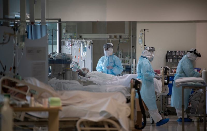 Healthcare workers attend to COVID-19 coronavirus patients at the Intensive Unit Care of the CEMTRO private clinic in Madrid on April 17, 2020. - Spain's death toll increased to nearly 19,500, government figures showed. The country reported 585 new fatalities in the past 24 hours, but said it had revised its counting mechanism, making the figures difficult to compare with previous tolls. (Photo by PIERRE-PHILIPPE MARCOU / AFP)