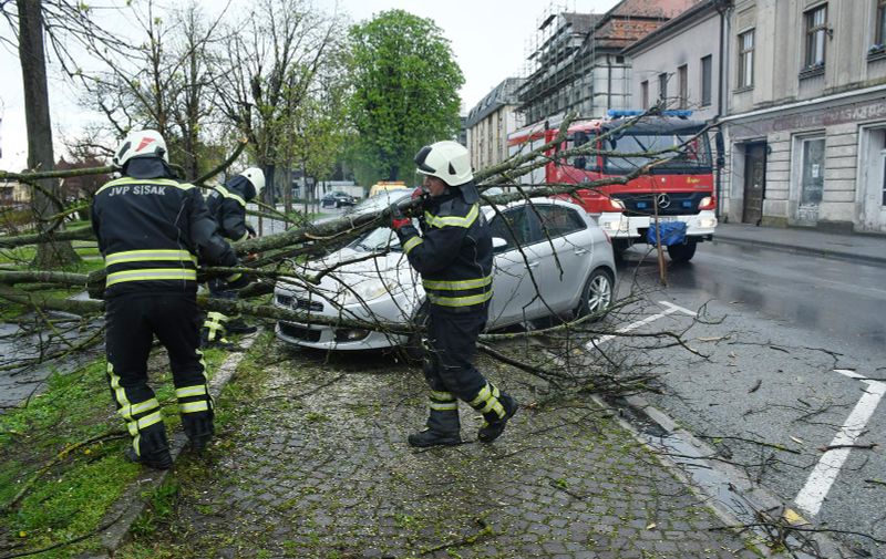 27.03.2023.,Sisak - Sisacki vatrogasci morali su rezati ostatke drveta koje je puknulo pod naletom jakog vjetra i ostetilo parkirani automobil u Rimskoj ulici.  Photo: Nikola Cutuk/PIXSELL