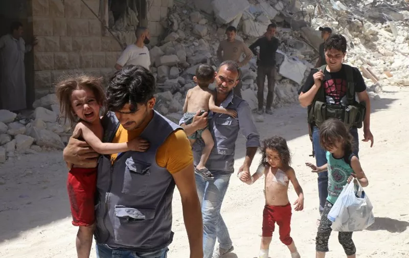 Syrian men carry injured children amid the rubble of destroyed buildings following reported air strikes on the rebel-held neighbourhood of Al-Mashhad in the northern city of Aleppo, on July 25, 2016.
Air strikes and barrel bomb attacks killed 16 civilians in rebel-held parts of Aleppo province, with rebel rocket fire onto government areas killing three more, the Britain-based Syrian Observatory for Human Rights said. / AFP PHOTO / Baraa Al-Halabi