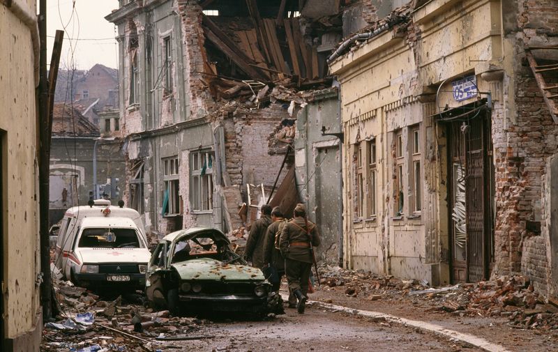 Yugoslavian soldiers and Serb paramilitaries, including Zeljko "Arkan" Raznatovic, walk past bombed buildings riddled with bullet holes and streets filled with rubble after a three-month battle between the Croatian armed forces and the Yugoslavian Federal Army in Vukovar. The Yugoslavian Federal Army completely destroyed the Croatian city, killing thousands of civilians, while the Serbian Volunteer Guard, formed by Raznatovic, was responsible for massive ethnic cleansing campaigns against Bosnian Croats., Image: 15114608, License: Rights-managed, Restrictions: Content available for editorial use, pre-approval required for all other uses.
This content may not be materially modified or used in composite content., Model Release: no, Credit line: Profimedia, Corbis