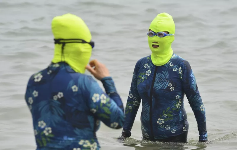 This photo taken on June 24, 2023 shows women clad in facekinis cooling off in the water amid hot weather in Qingdao, in China's eastern Shandong province. (Photo by AFP) / China OUT