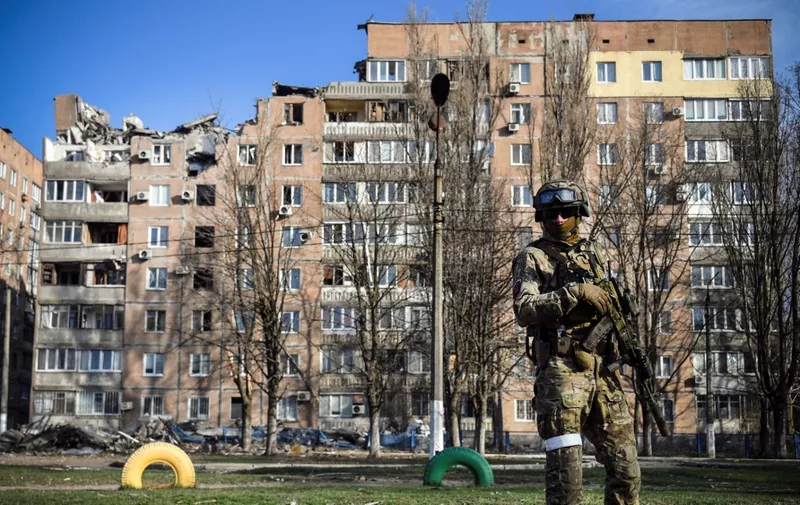 A Russian soldier stands in front of an apartment building on April 11, 2022, in Donetsk, capital of the self-proclaimed Donetsk People's Republic (DNR), which the Russian authorities say was damaged by Ukrainian shelling. The picture was taken during a trip organized by the Russian military. (Photo by Alexander NEMENOV / AFP)