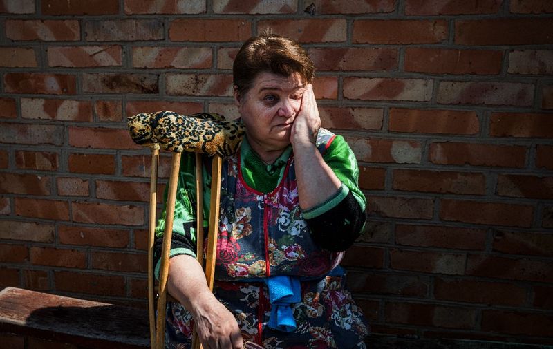 Nyna Provontsova, 65, reacts during a conversation with social worker Zhanna Protsenko in the town of Orikhiv, near Zaporizhzhia, eastern Ukraine, on May 11, 2022, amid the Russian invasion. - Shelling thundered in several directions and black smoke drifted upward in the distance as Zhanna Protsenko pedalled off for her rounds in her war-battered Ukrainian town. Shes a social worker who has decided to stay behind despite the risk to herself because the people she is tasked with caring for wont or simply cant evacuate  so shes staying too. (Photo by Dimitar DILKOFF / AFP)
