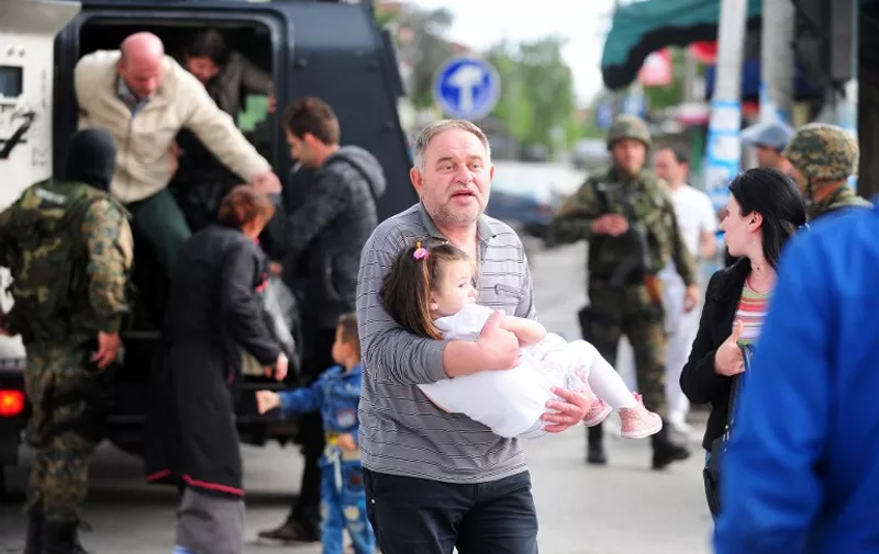 A man holding a child gets out an APC (Armored Personnel Carriers) transporting the local population out of the conflict zone in Kumanovo, northern Macedonia, on May 9, 2015 after clashes in which four policemen were injured. The clashes took place during a dawn police raid in a part of the town populated mainly by ethnic Albanians in what a spokesman described as an operation against an "armed group", heightening fears of instability in the ex-Yugoslav republic after months of political crisis. AFP  PHOTO / ROBERT ATANASOVSKI