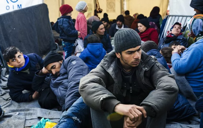 People sit near the gate at the Greek-Macedonian border near the Greek village of Idomeni where thousands of refugees and migrants are stranded on March 8, 2016.
European Union leaders on March 7 hailed a "breakthrough" in talks with Turkey on a deal to curb the migrant crisis but delayed a decision until a summit next week to flesh out the details of Ankara's new demands. More than one million refugees and migrants have arrived in Europe since the start of 2015 -- the majority fleeing the war in Syria -- with nearly 4,000 dying while crossing the Mediterranean. / AFP / DIMITAR DILKOFF