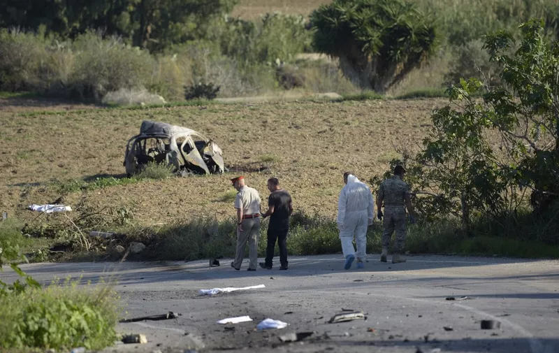 Police and forensic experts inspect the wreckage of a car bomb believed to have killed journalist and blogger Daphne Caruana Galizia close to her home in Bidnija, Malta, on October 16, 2017. The force of the blast broke her car into several pieces and catapulted the journalist's body into a nearby field, witnesses said. She leaves a husband and three sons. - Caruana Galizia's death comes four months after Prime Minister Joseph Muscat's Labour Party won a resounding victory in a general election he called early as a result of scandals to which Caruana Galizia's allegations were central. (Photo by STR / AFP) / Malta OUT