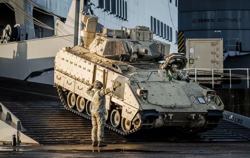 This photograph taken on January 11, 2023, shows a soldier guiding a US Army Bradley Fighting Vehicle (BFV) as it disembarks in the Dutch port of Vlissingen, as US military equipment and vehicles travel to Poland and Lithuania. (Photo by Remko de Waal / ANP / AFP) / Netherlands OUT