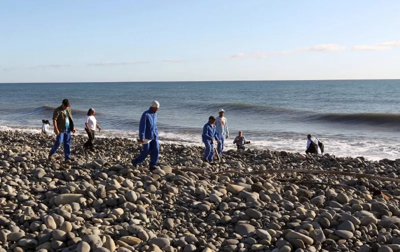 Volunteers of the "3 E" (Eastern Environnement and Economy) association usually in charge of coastal cleaning, who found a plane debris and a piece from a luggage on July 29, search for more potential plane debris and items on the shore in Saint-Andre, Reunion Island, on July 31, 2015. Australia on July 31 said it was confident the search for MH370 was being conducted in the right area with aircraft wreckage being washed to La Reunion consistent with the zone they are scouring. AFP PHOTO / IMAZ PRESS REUNION / OUISSEM GOMBRA