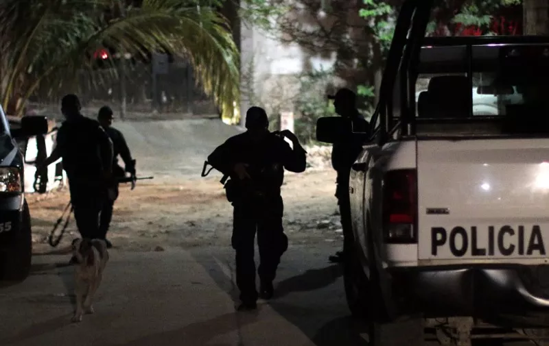 Police officers patrol the murder crime scene at Las Cruces neighbourhood in Acapulco, Guerrero state, Mexico on January 21, 2016. Guerrero is one of Mexico's poorest and most violent states, where a lucrative drug trade has flourished. / AFP / Pedro Pardo