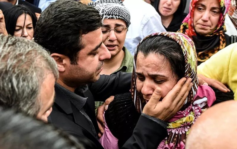Leader of Turkey's pro-Kurdish Peoples' Democracy Party (HDP) Selahattin Demirtas (L) mourns with the relative of a victim of yesterday's attack in an area allocated for families outside a forensic morgue, as they wait for the bodies of relatives, on October 11, 2015 in Ankara. Turkey woke in mourning on October 11 after at least 95 people were killed by suspected suicide bombers at a peace rally of leftist and pro-Kurdish activists in Ankara, the deadliest such attack in the country's recent history. AFP PHOTO / OZAN KOSE