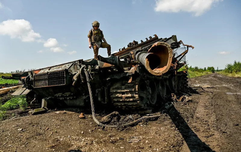 NOVODARIVKA, UKRAINE - JULY 21, 2023 - A press officer who goes by callsign Damian stands on top of a destroyed Russian military vehicle in Novodarivka village, Zaporizhzhia Region, southeastern Ukraine. Situated on the border between Zaporizhzhia and Donetsk Regions, the settlement that had been occupied since March 2022 was liberated by the Ukrainian military on June 4, 2023. NO USE RUSSIA. NO USE BELARUS. (Photo by Ukrinform/NurPhoto) (Photo by Dmytro Smolienko / NurPhoto / NurPhoto via AFP)