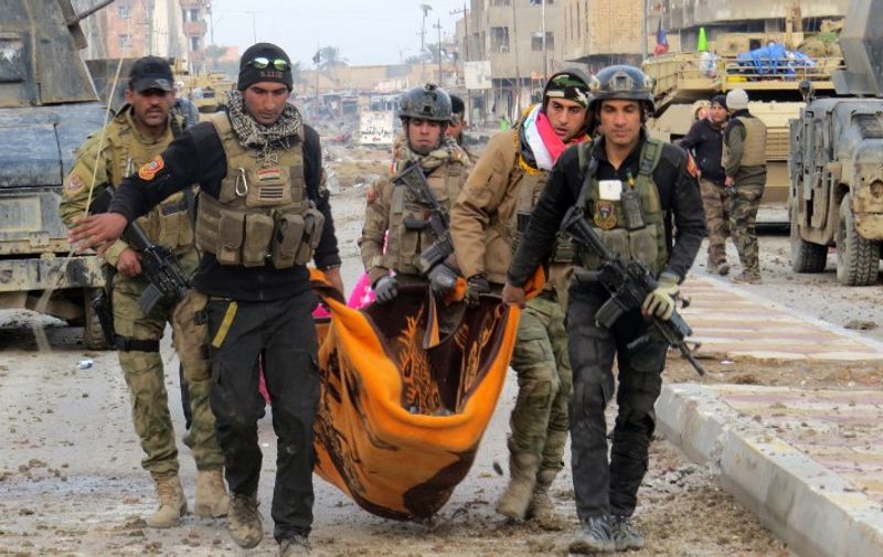 Iraqi government forces and members of Iraq's elite counter-terrorism service carry the body of a comrade during battles with Islamic State (IS) group jihadists as they try to secure all the neighbourhoods of Ramadi, the capital of Iraq's Anbar province, about 110 kilometers west of the capital Baghdad, on January 1, 2016.  Iraq declared the city of Ramadi liberated from the Islamic State group on December 28 and raised the national flag over its government complex after clinching a landmark victory against the jihadists. AFP PHOTO / STR / AFP / STR