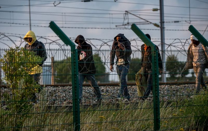 Migrants who successfully crossed the Eurotunnel terminal walk on the side of the railroad as they try to reach a shuttle to Great Britain, on July 28, 2015 in Frethun, northern France. About 2,000 migrants tried to enter the Eurotunnel terminal in the French port town of Calais overnight in a desperate bid to reach England through the Channel tunnel, a spokesman said July 28. AFP PHOTO / PHILIPPE HUGUEN