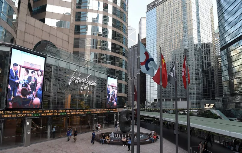 This general view shows the flag (C) of the Stock Exchange of Hong Kong flying next to the Chinese national flag (2nd L) and the Hong Kong SAR flag (R), outside the exchange offices in the Central district of Hong Kong on September 11, 2019. - The Hong Kong Stock Exchange has bid almost 40 billion USD for its London rival to bring together the largest financial hubs in Asia and Europe, it said on September 11. (Photo by Nicolas ASFOURI / AFP)