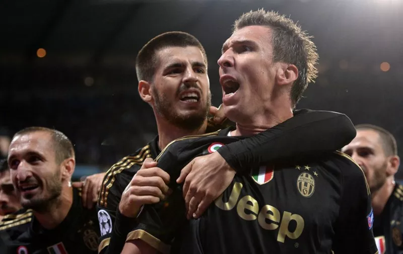 Juventus' forward from Croatia Mario Mandzukic (C) celebrates with Juventus' forward from Spain Alvaro Morata (L) after scoring during a UEFA Champions League group stage football match between Manchester City and Juventus at the Etihad stadium in Manchester, north-west England on September 15, 2015.    AFP PHOTO / OLI SCARFF