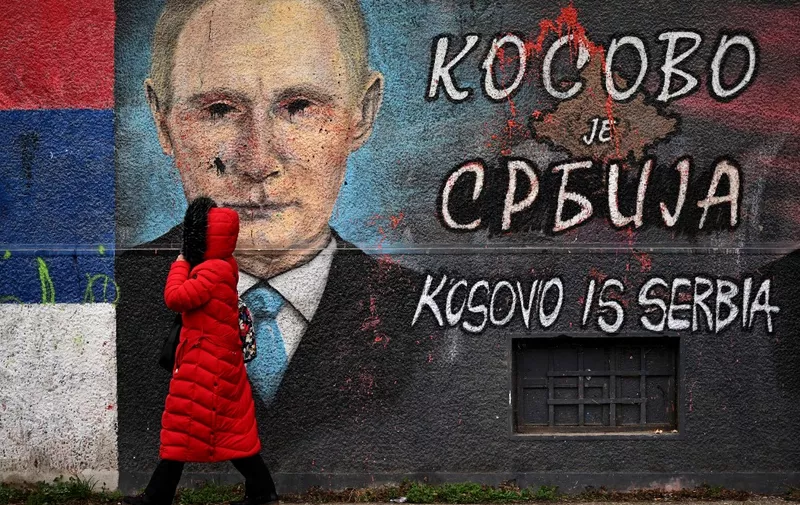A pedestrian walks past a mural painting representing the portrait of Russia's President Vladimir Putin (L) and the map of Kosovo with both cyrillic and english writing, reading "Kosovo is Serbia", in Belgrade on January 23, 2023. - On January 23, 2023, Serbia's President joined his Prime Minister and her cabinet for a special session on Kosovo to discuss current international brokered dialogue for the normalization of relations between Serbia and Kosovo. (Photo by Andrej ISAKOVIC / AFP)