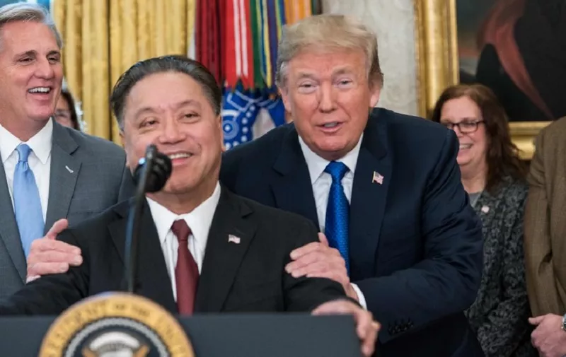 US President Donald Trump jokes with Broadcom CEO Hock Tan as he announces that Broadcom woud be moving back to the US in the Oval Office at the White House in Washington, DC, on November 2, 2017. / AFP PHOTO / NICHOLAS KAMM